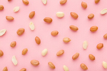 Brown almond nuts on light pink table background. Pastel color. Closeup. Food pattern. Top down view.