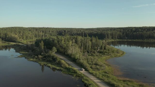 Truck And Car Driving On The Road Through Lakes In Boreal Forest, Saskatchewan, Canada. aerial