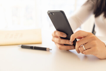 woman hands holding smartphone with notepad and pen in backlight