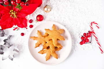 Snowflake shaped homemade Christmas cookies on the plate with Christmas decoration on the background