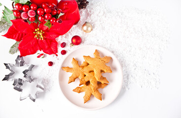 Snowflake shaped homemade Christmas cookies on the plate with Christmas decoration on the background