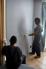 Fototapeta premium Workmen measuring wall with tape before tv installation