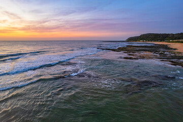 Naklejka premium Aerial dawn seascape with high cloud and gentle surf