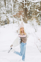 Fototapeta na wymiar Happy beautiful girl wearing warm winter clothes ice skating in the park
