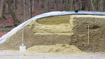 Silage pile - animal food mainly used for cows. With a shovel and a pitchfork leaning on the silage pile.