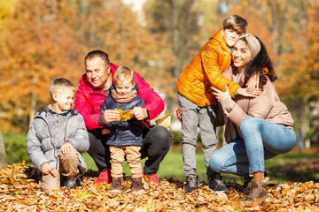 Happy young family with three children in the autumn park. Love and tenderness. Walk in the golden season.