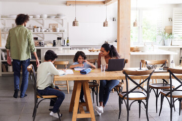 Family in kitchen with sons doing homework