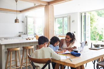 Mother with sons doing homework in kitchen