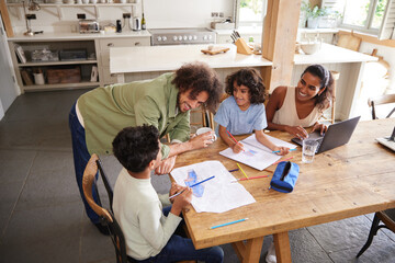 Boys drawing on kitchen table with parents, high angle