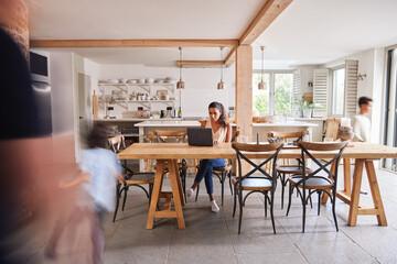 Woman working at home on laptop in kitchen