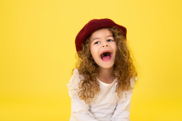 Portrait of a little curly 3-year-old girl with a hat on her head