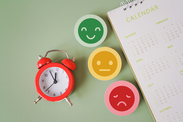 Obraz premium top view of red analog alarm clock , facial emotional and blurred yearly calendar on green background