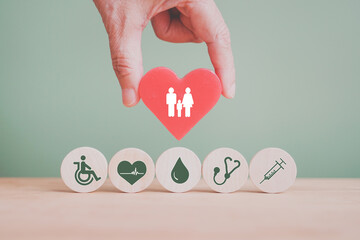 hand holding red heart with family icon with health and medical icon on circle wood for family...