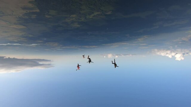 Freefly skydiving. Four skydiver are flying in the sky.  One skydiver is head down flying. Video head down.