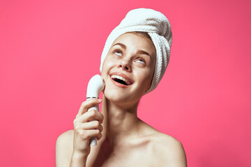 woman with towel on head cleaning skin naked shoulders pink background