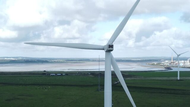 Alternative green energy wind farm turbines spinning in Frodsham Cheshire fields aerial view slow left orbit