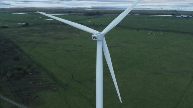 Alternative green energy wind farm turbines spinning in Frodsham Cheshire fields aerial view high left orbit