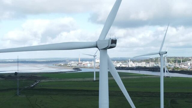 Alternative green energy wind farm turbines spinning in Frodsham Cheshire fields aerial view closeup orbit left