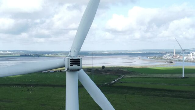 Alternative green energy wind farm turbines spinning in Frodsham Cheshire fields aerial view closeup orbit right