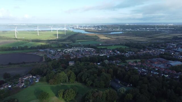 Cheshire farmland countryside wind farm turbines generating renewable green energy aerial view pan left
