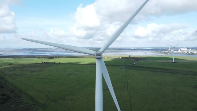 Alternative green energy wind farm turbines spinning in Frodsham Cheshire fields aerial view closeup pull back