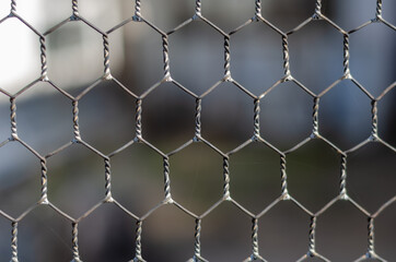 Woven wire fence in close-up. Repeated hexes of galvanized wire.