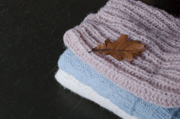 A stack of knitted sweaters on a dark background. Autumn theme.