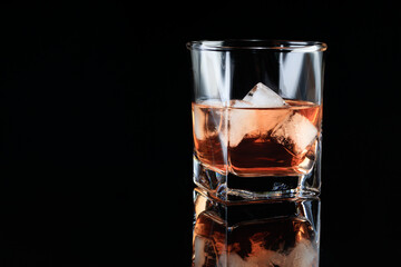 Glass of whiskey with ice on a glass background. Soft focus.