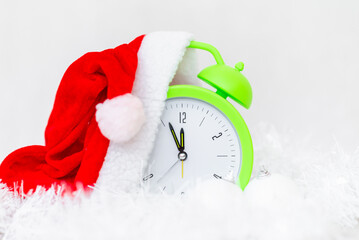 Alarm clock with Santa hat and Christmas decorations isolated on gray white background.New Year 2022 concept.