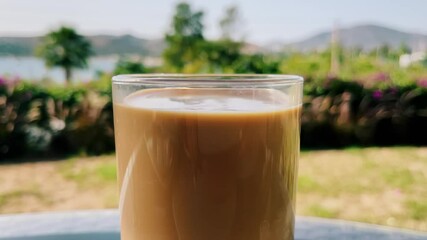 Coffee with milk, cup on table outdoors in summer. High quality 4k footage