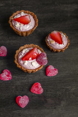 vegan tartlets with fresh strawberries and marmalade in the shape of a heart on a dark wooden background, top view. dessert for valentine's day