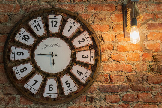 a clock and lamp hanging on a red brick wall. Selective Focus Clock