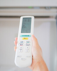 リモコンを操作してエアコンをつける手元　イメージ