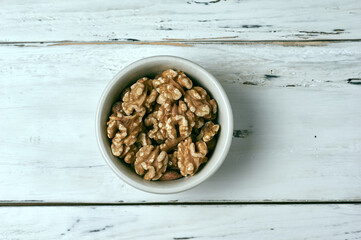 Bowl of walnuts on a rustic white wooden table