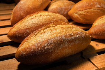 Close-up of sourdough bread. Freshly baked bread with a golden crust on the wooden shelves of the bakery. The context of a German artisan bakery with an assortment of rustic breads.