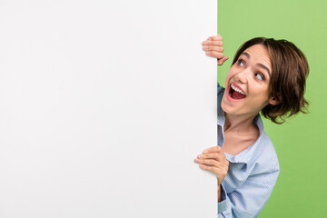Photo of amazed shocked excited joyful happy woman look empty space white banner isolated on green color background