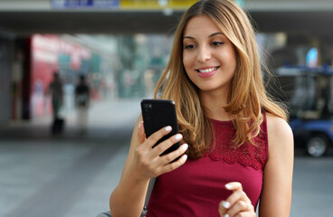 Close-up of charming beautiful business woman smile in casual style using smartphone walking in train or metro station. Copy space. - obrazy, fototapety, plakaty