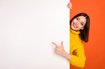 Photo of young woman happy positive smile point finger empty space billboard ad advice choice...