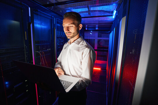 System technician running diagnostic of server racks with laptop