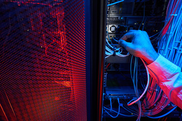 Hand of technician connecting twisted pair cable to server