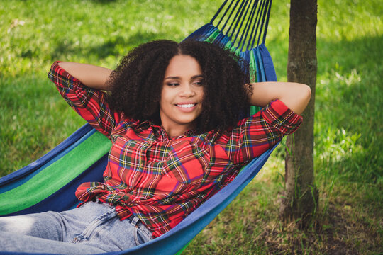 Photo portrait woman in city park laying in hammock relaxing wearing plaid shirt blue jeans