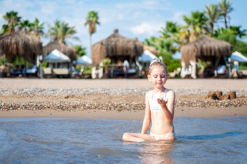 Little girl playing on the beach by the sea