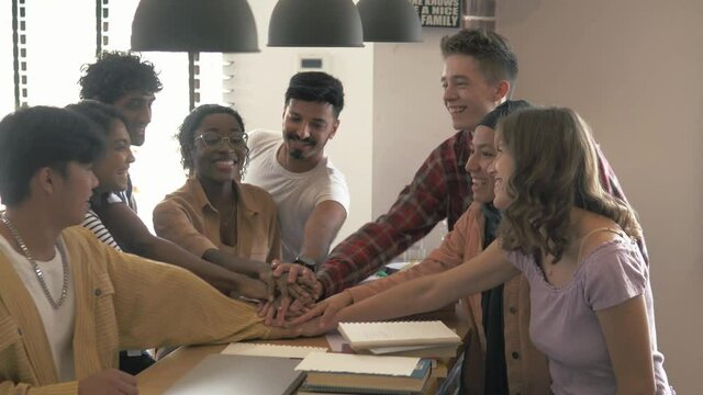 Close-up happy diverse adult business people students joining hands together. Team spirit at modern multiethnic loft office. Students celebrate successful exam by joining hands together