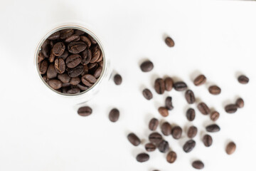 Roasted coffee beans in clear glass on white background.