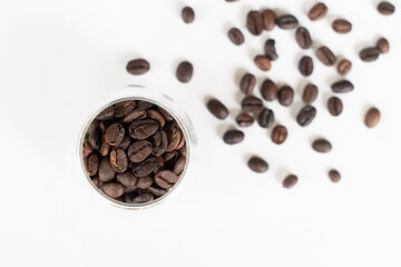 Roasted coffee beans in clear glass on white background.