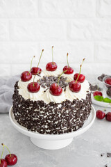 Black forest cake, Schwarzwald pie. Cake with dark chocolate, whipped cream and cherry on a gray concrete background. Copy space.