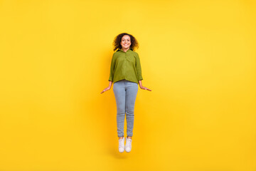 Photo of funky positive charming pretty woman dressed green shirt jumping high smiling isolated yellow color background