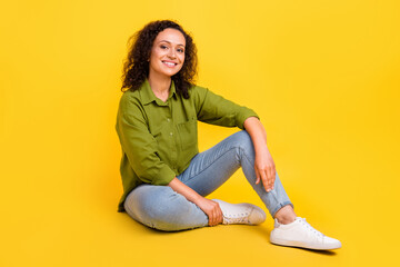 Photo of sweet shiny charming lady wear green shirt smiling sitting floor having rest isolated yellow color background