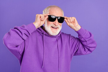 Obraz premium Portrait of attractive cheerful grey-haired man touching specs good mood isolated over bright violet purple color background