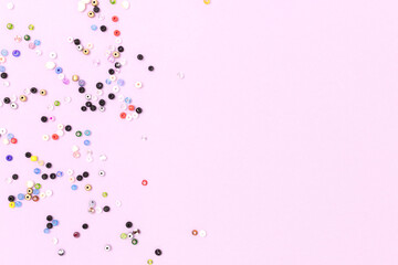 Multicolored beads scattered on a purple background with copyspace.